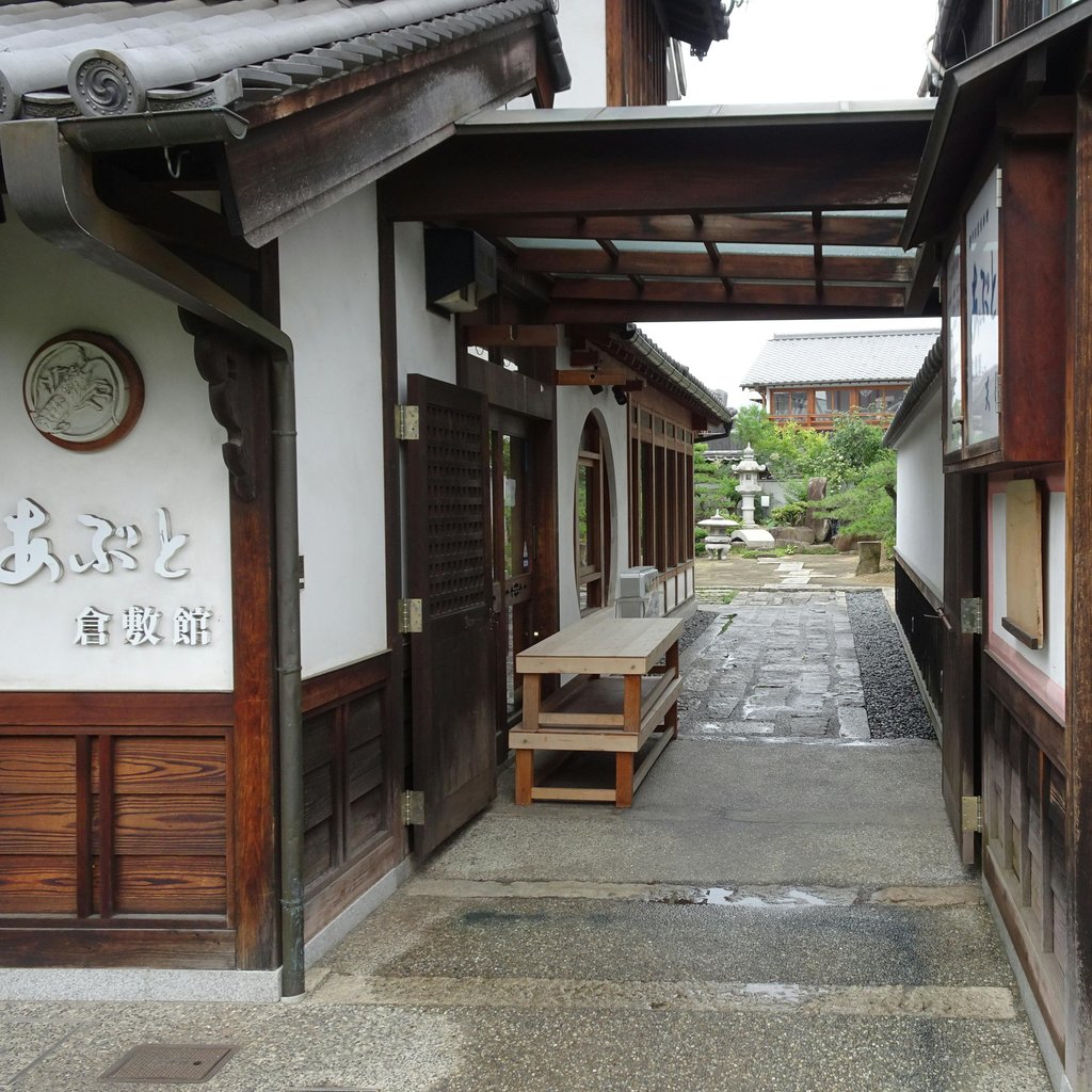 Charming view of a traditional Japanese alleyway in Kurashiki, showcasing wooden architecture and a serene path.