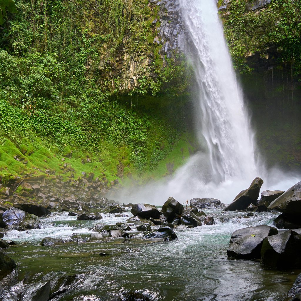 Explore the vibrant La Fortuna Waterfall with lush greenery and rugged rocks.