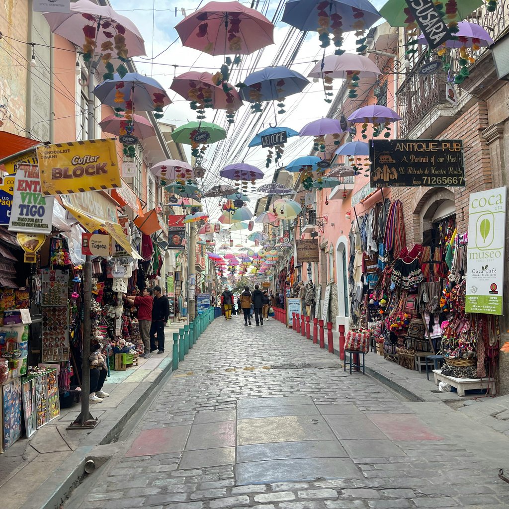 Colorful umbrellas decorate a bustling market street in La Paz, Bolivia.