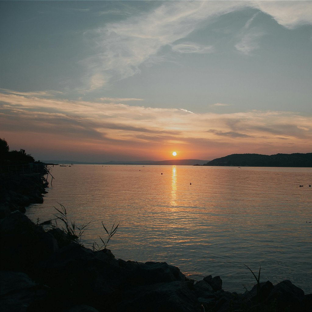 Captivating sunset view across Lake Balaton, emphasizing serene water and scenic horizon.