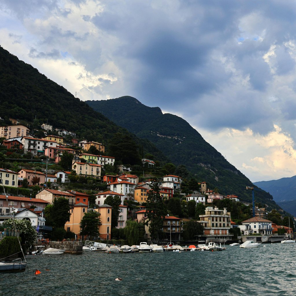 Picturesque view of Lake Como with colorful houses and Italian flag waving.