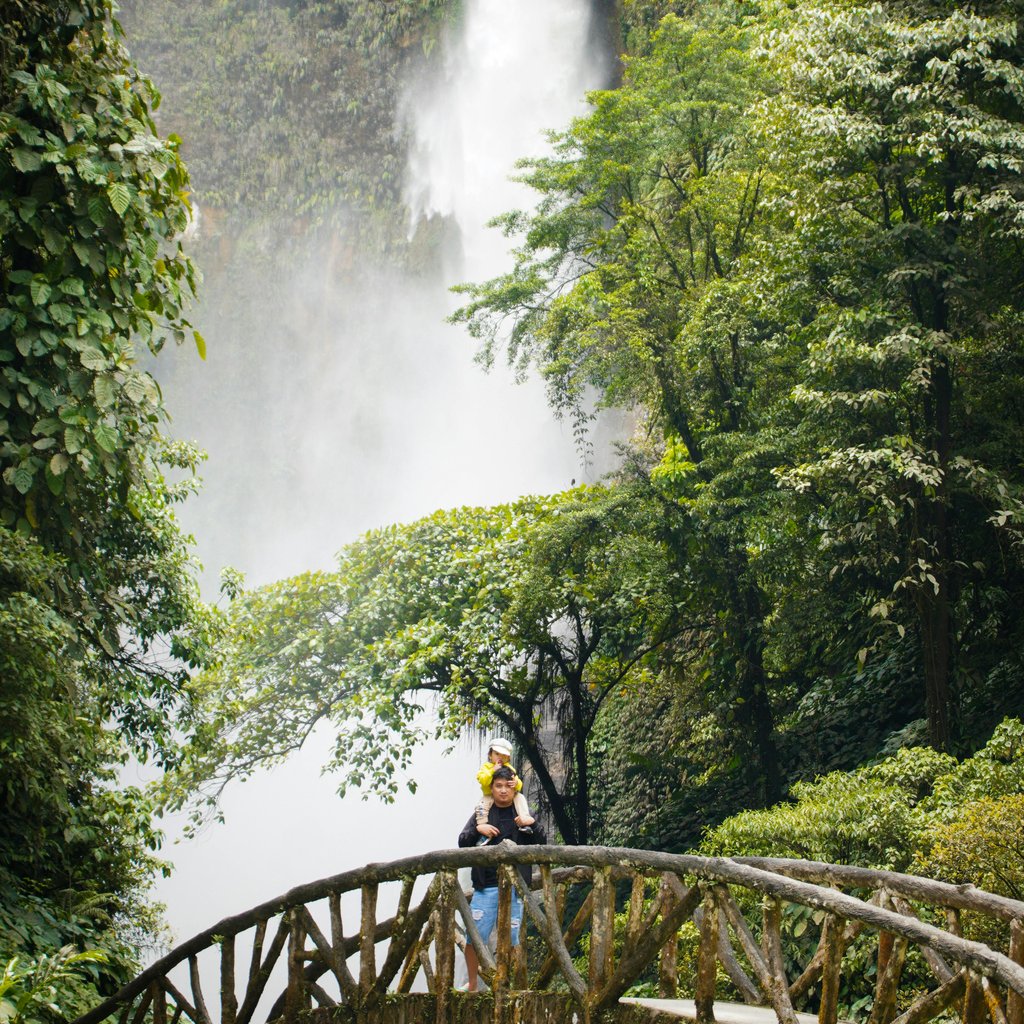 Father and child enjoy the scenic view of a waterfall at Lake Sebu, Philippines.