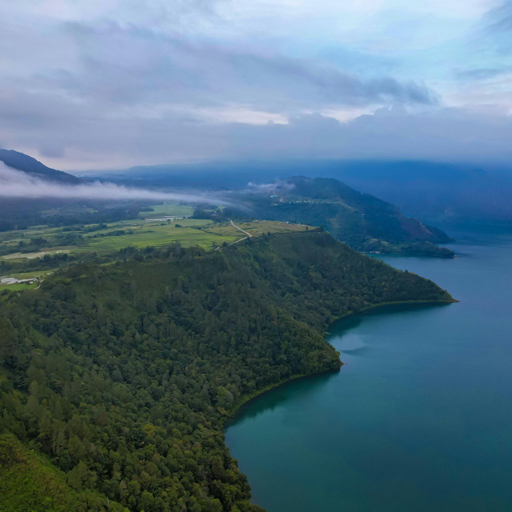 Scenic aerial view of Lake Toba's lush green coastline in North Sumatra, Indonesia.