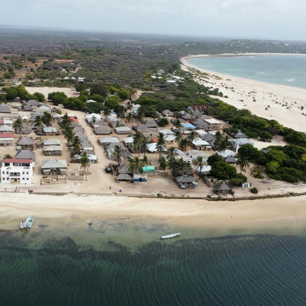 A stunning aerial shot of a coastal village in Lamu County, Kenya, featuring sandy beaches and clear ocean waters.