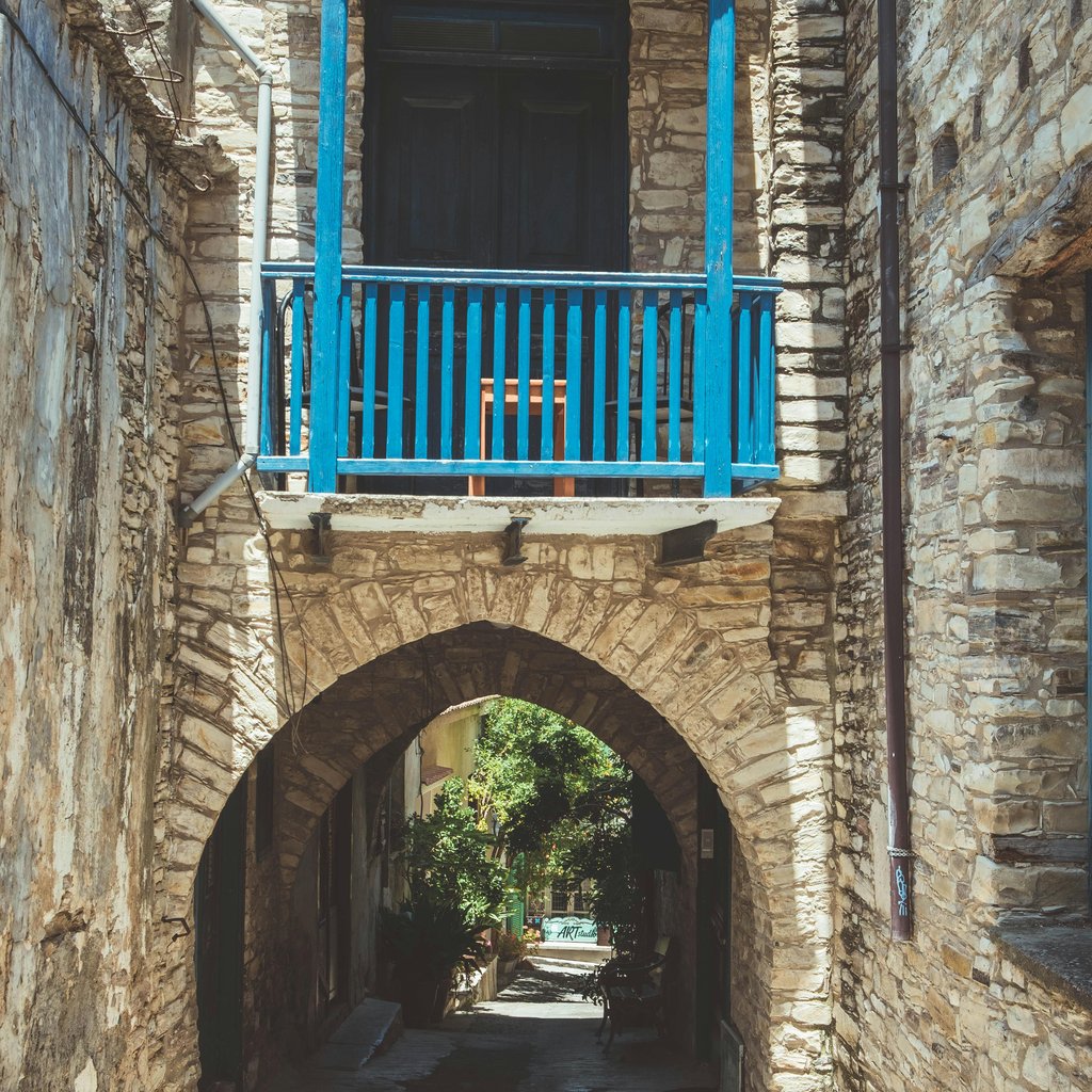 Rustic stone archway with blue balcony in Pano Lefkara, Cyprus.
