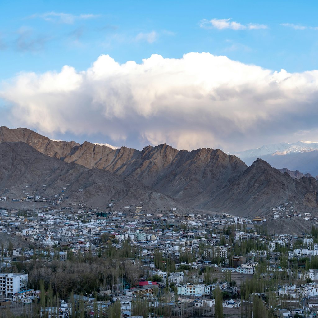 Breathtaking view of Leh town surrounded by towering mountains and clear blue skies.
