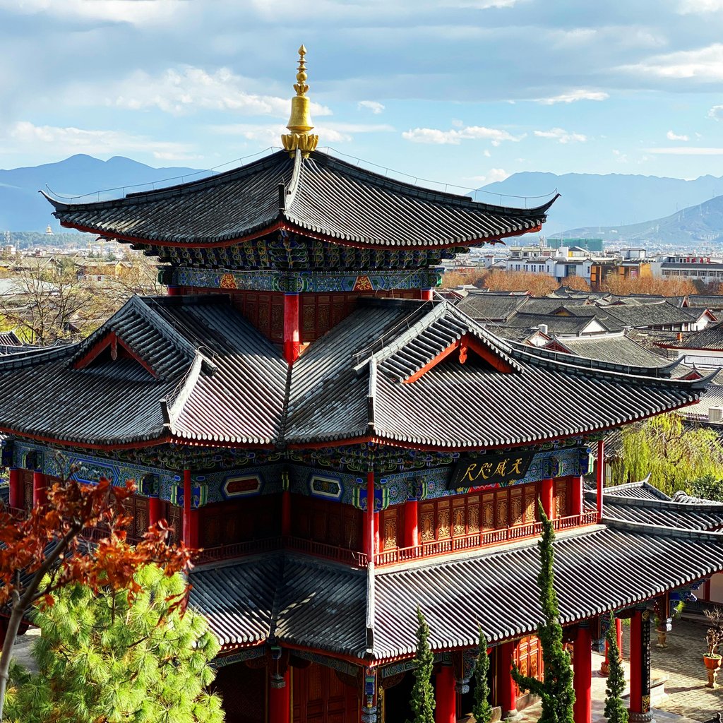 Stunning view of a traditional pagoda at Mufu Palace in Lijiang, China, under a bright blue sky.