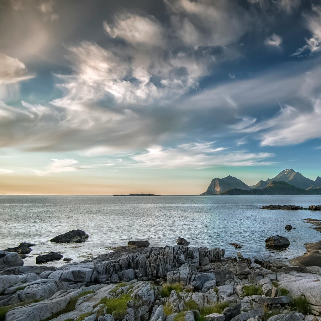 Serene coastal view of Sandnes, Norway with mountains and a vibrant sky.