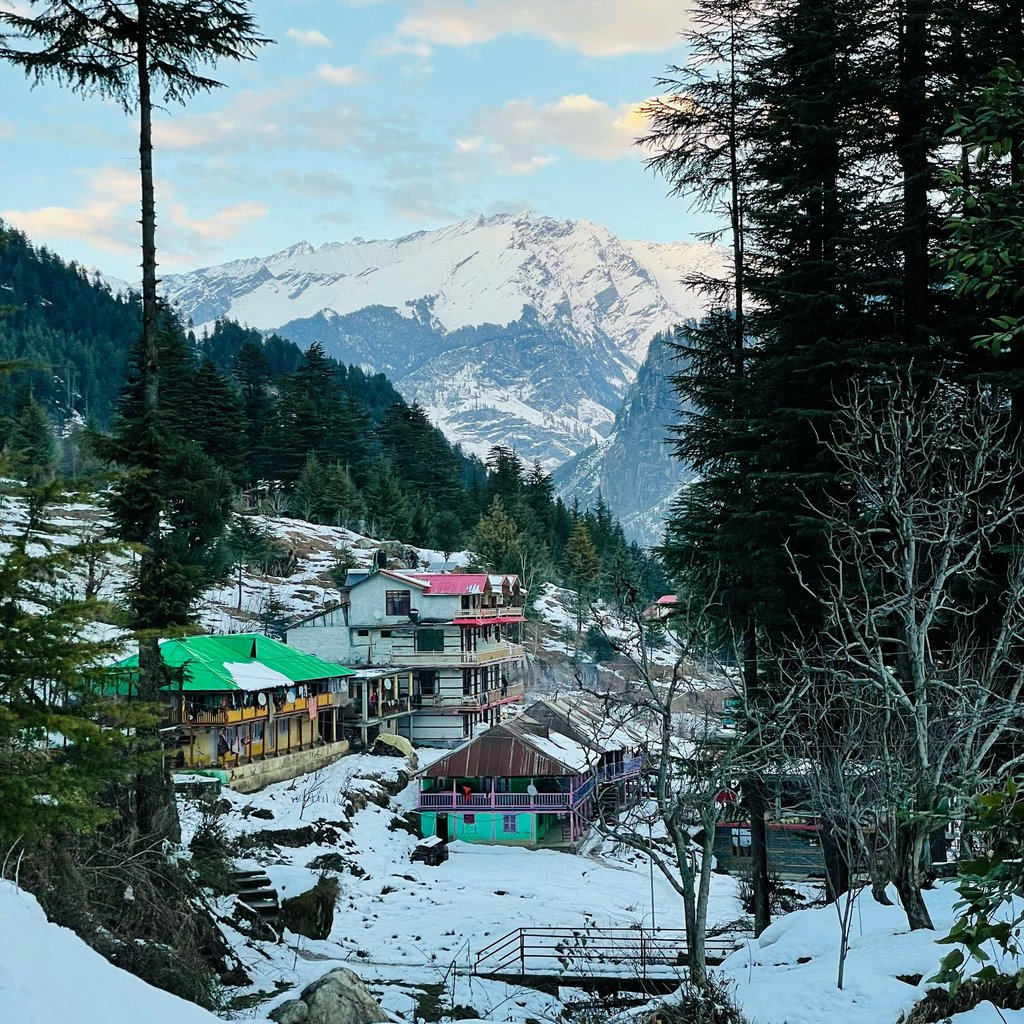 Charming winter view of snow-covered Manali buildings and mountains in Himachal Pradesh.
