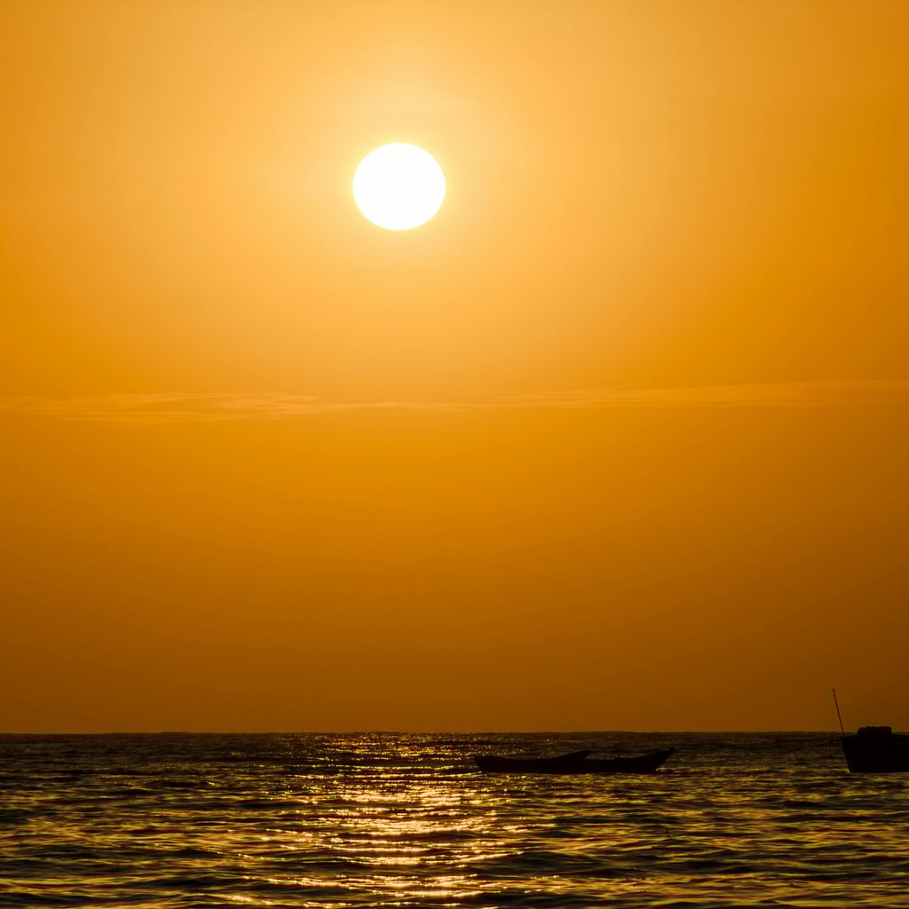 A stunning sunset view with a boat silhouette in Máncora, Peru. Vibrant and dramatic.