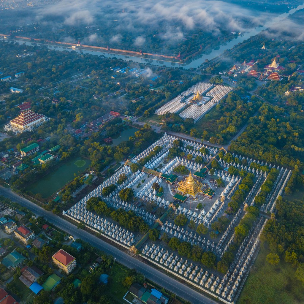 Stunning aerial view of Kuthodaw Pagoda surrounded by lush greenery in Mandalay, Myanmar.
