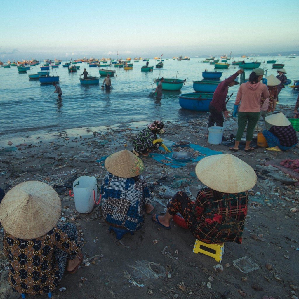 A vibrant morning scene of Vietnamese fishermen with boats on a bustling beach.