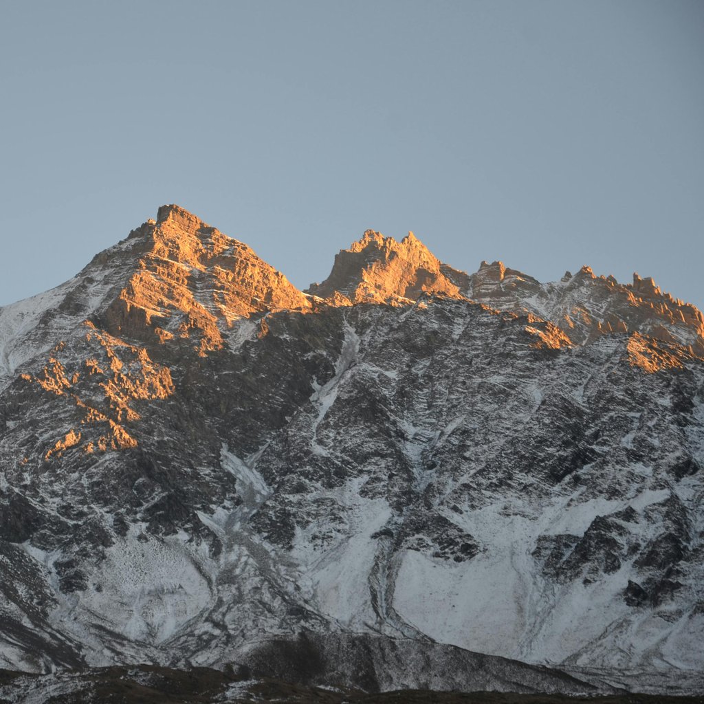 Capture of Muktinath mountains glistening with snow under a sunrise sky in Gandaki Province, Nepal.