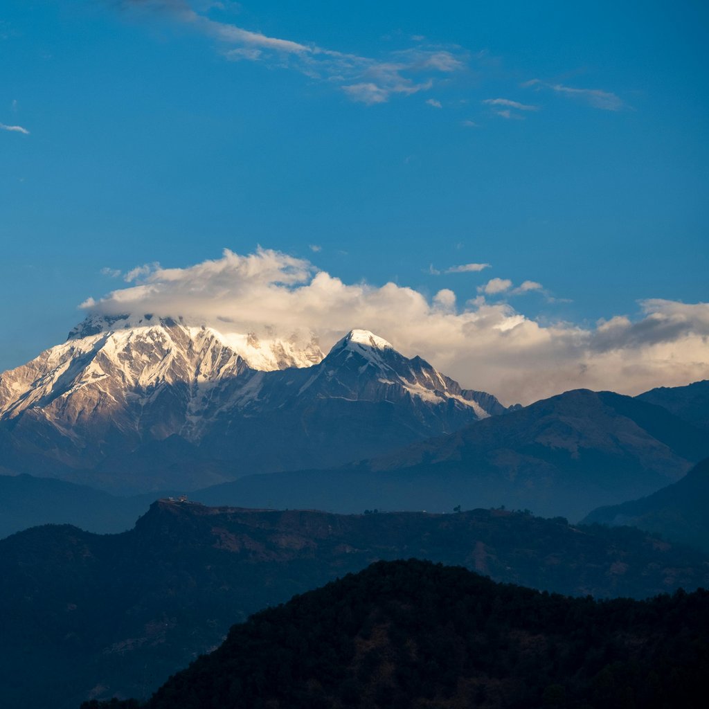 Stunning vista of the snow-capped Annapurna mountain range under a blue sky in Nepal.