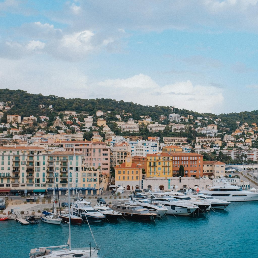Charming harbor in Nice with yachts and colorful Mediterranean buildings.