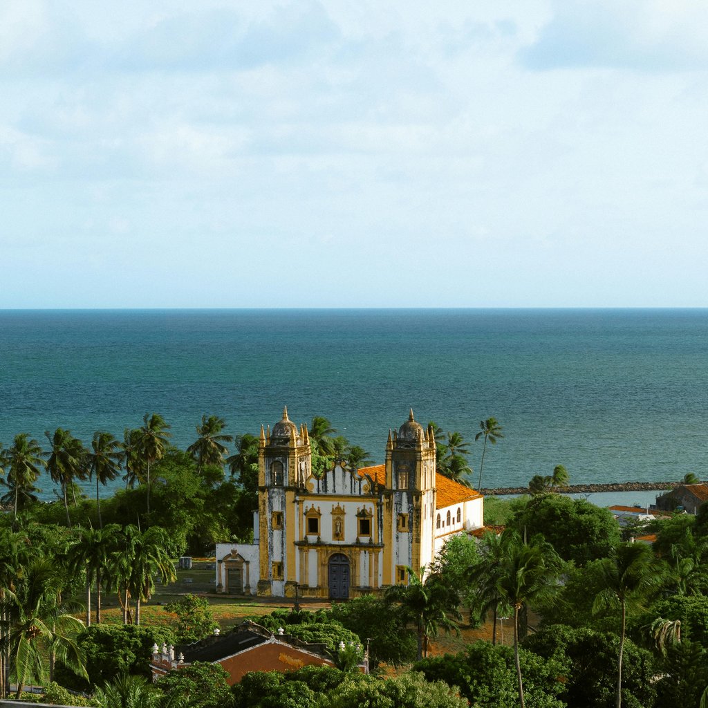 Scenic view of Igreja do Carmo and Atlantic Ocean in Olinda, Brazil, with lush greenery and palm trees.