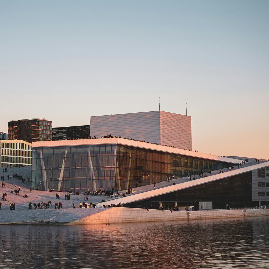 Captivating view of Oslo Opera House reflecting on water at sunset, showcasing modern architecture.