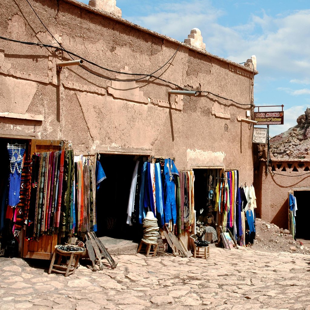 Colorful market stalls in Ouarzazate, Morocco with historic kasbah backdrop.