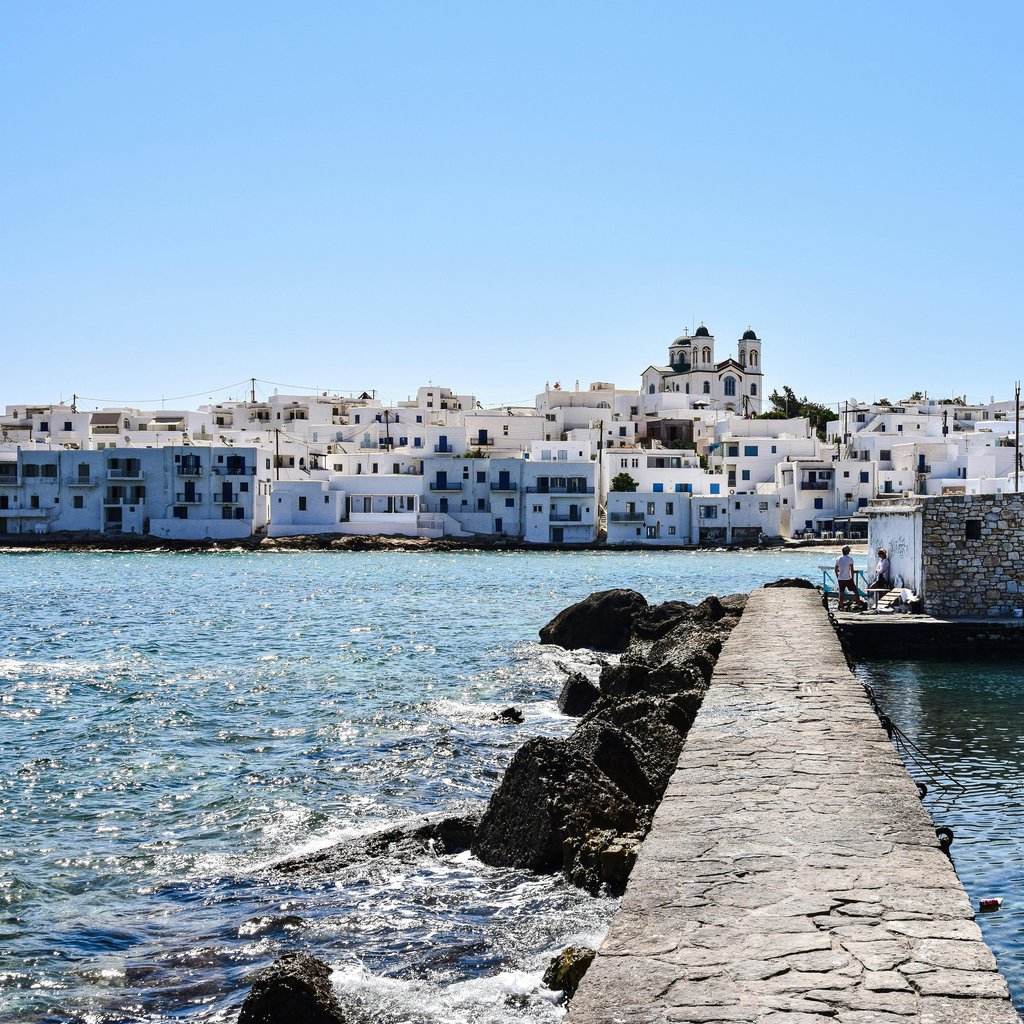 Charming white-washed buildings and boats along Paros Island's scenic waterfront pier.