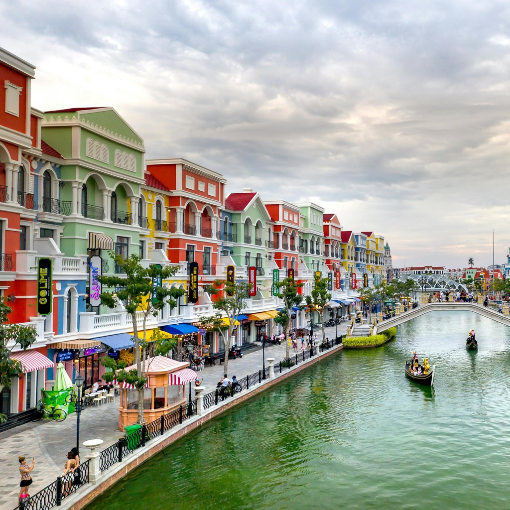 Colorful buildings line a vibrant canal with tourists enjoying a scenic view in Phu Quoc city, Vietnam.