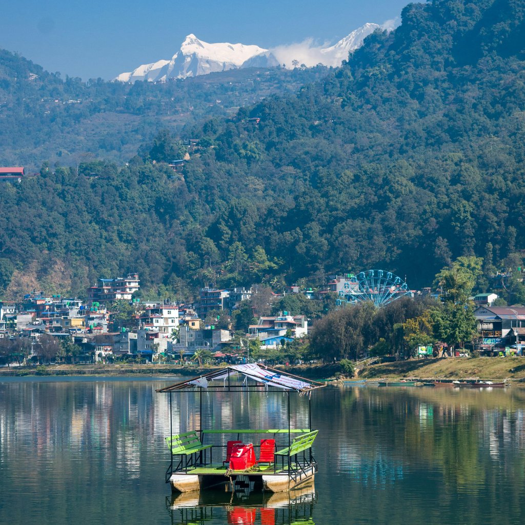 Tranquil scene of Phewa Lake with reflections and Himalayan mountains in Pokhara, Nepal.