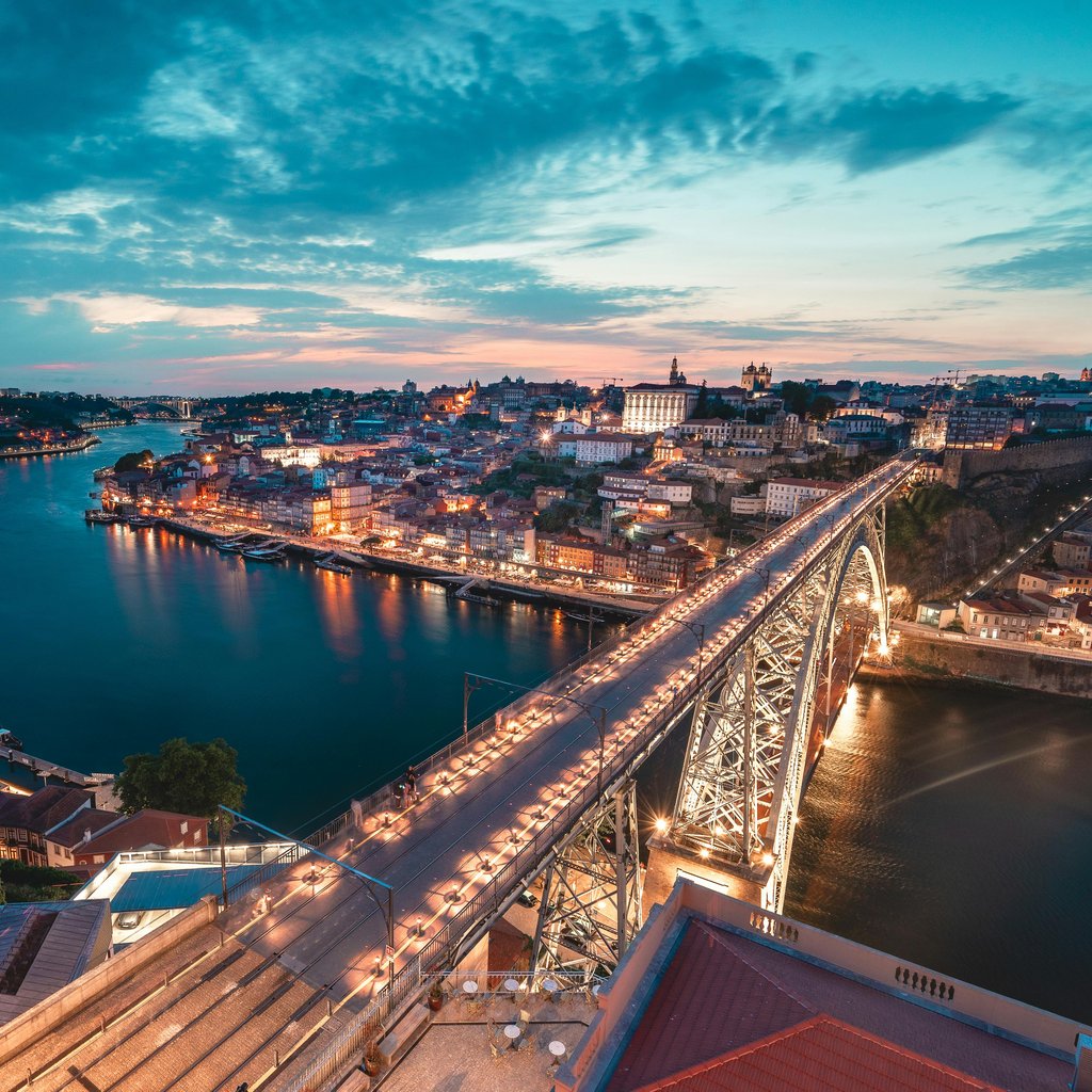 A breathtaking view of Porto, Portugal with the iconic bridge over the Douro River at twilight.