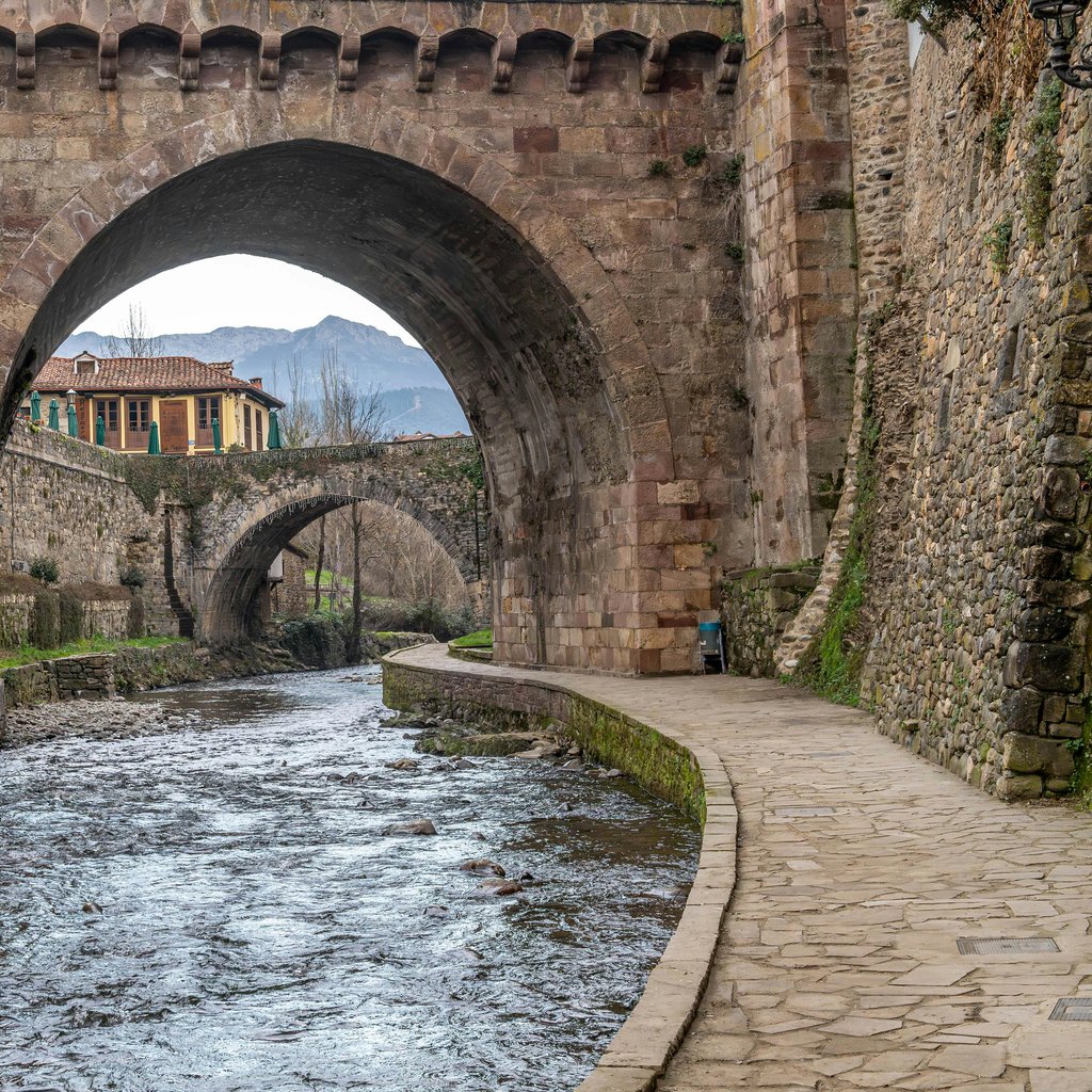 Beautiful medieval stone bridge over a flowing river in a historic Spanish town.