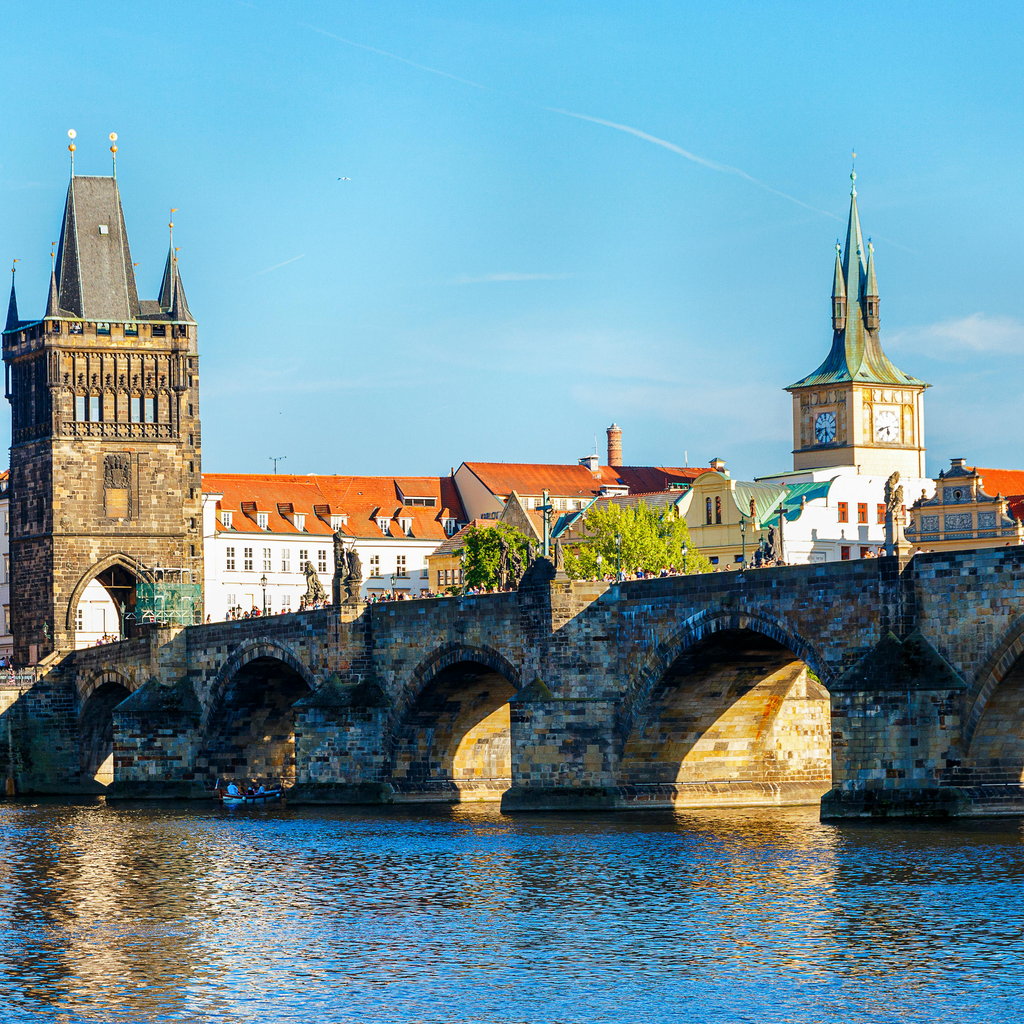 Stunning view of Charles Bridge and historic towers in Prague under a clear blue sky.