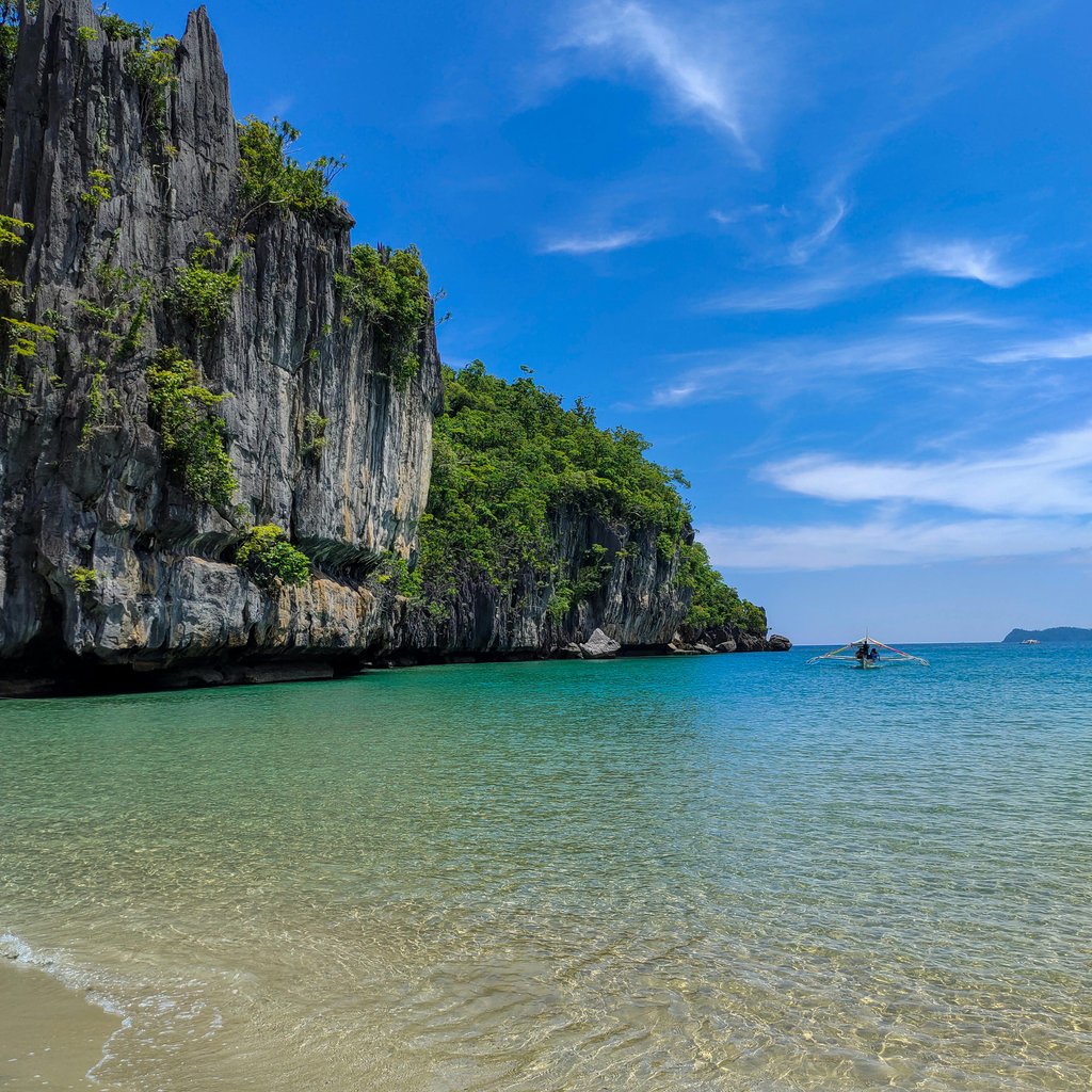 Captivating beach and cliffs in El Nido, Philippines under a vivid blue sky.