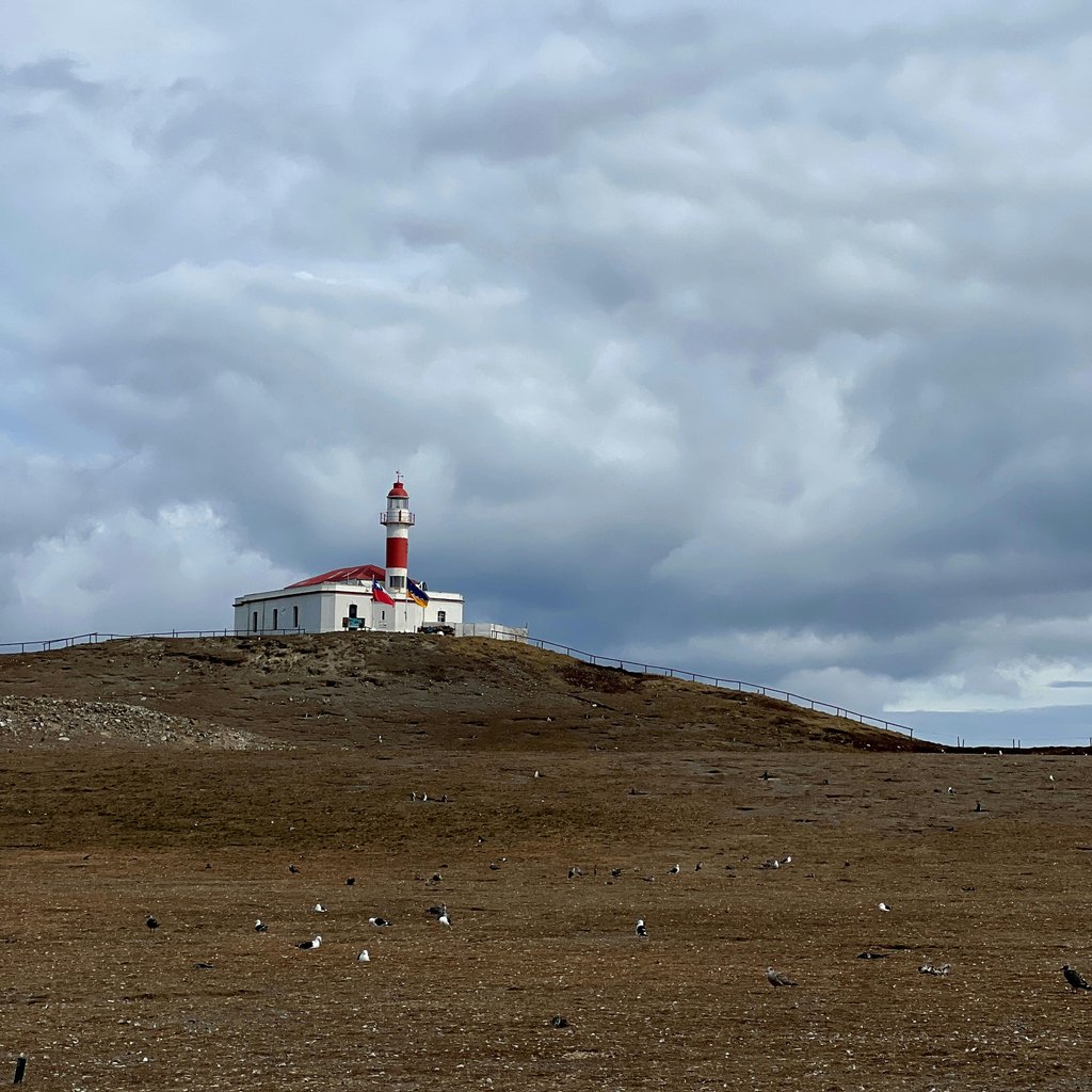 Lighthouse on Magdalena Island with cloudy skies, depicting a remote Chilean landmark.