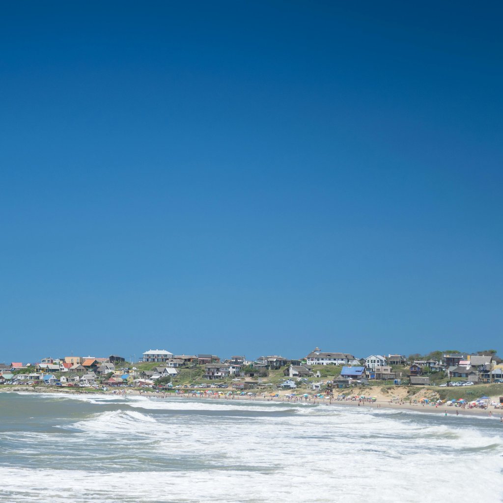 A picturesque coastal view of Punta del Diablo, Uruguay with vibrant blue skies and waves.