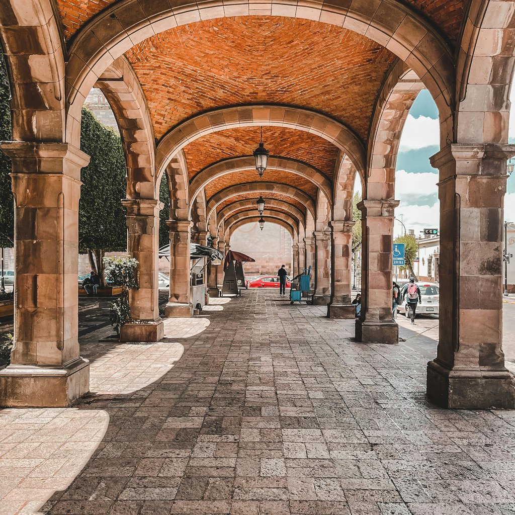 Brick archway with stone pillars in Santiago de Querétaro, Mexico, offering a glimpse of local architecture.