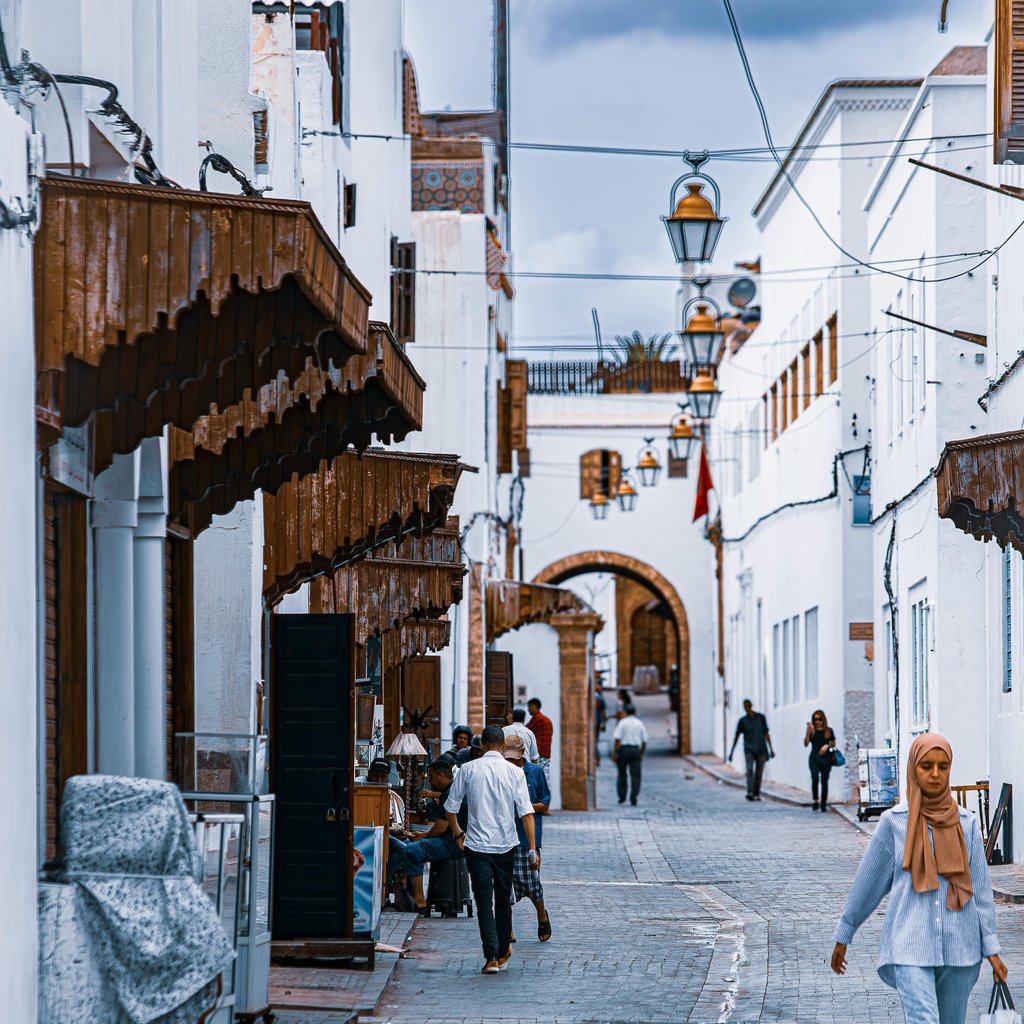 Scenic view of a Moroccan alley with traditional white buildings and street life. Ideal for travel and culture themes.