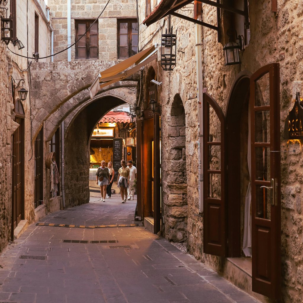 Charming cobblestone street in Old Town Rhodes with classic stone architecture and warm lighting.