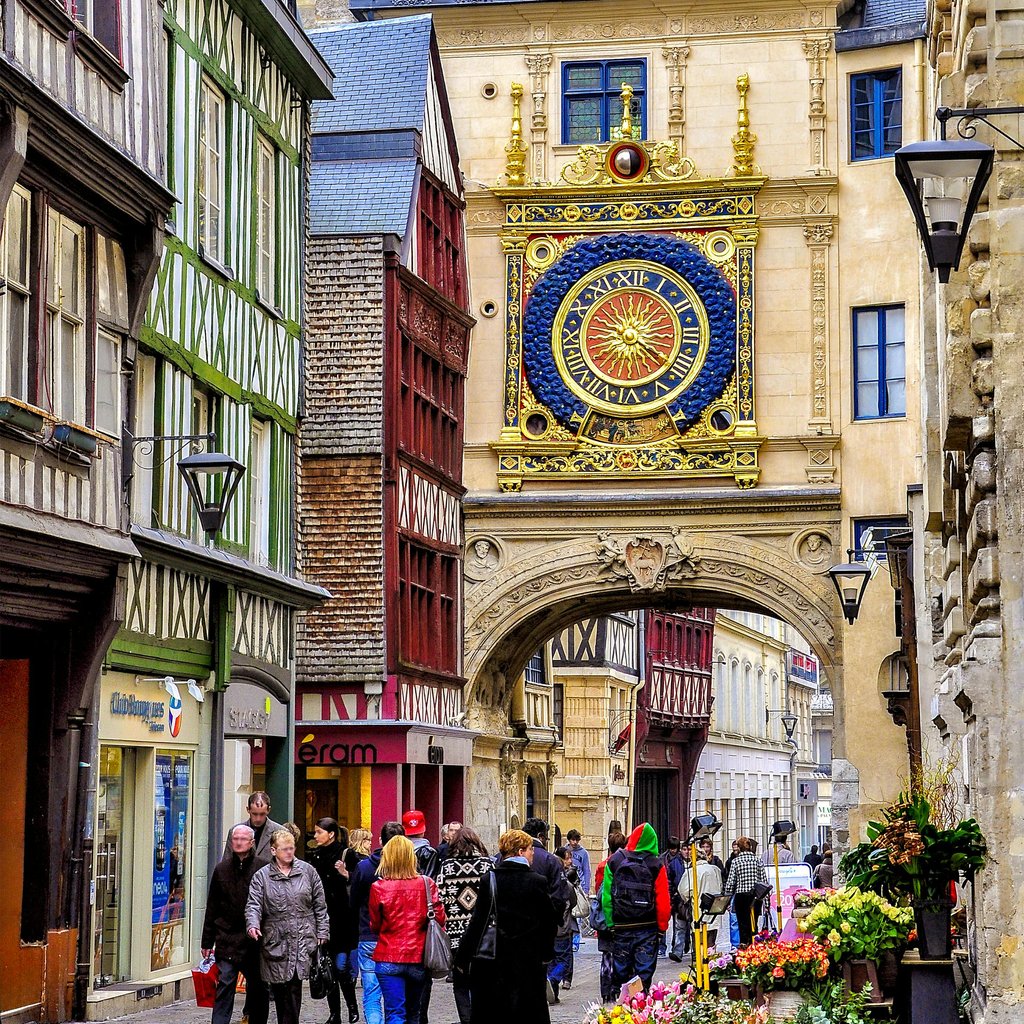 Vibrant street scene featuring Le Gros-Horloge in Rouen, France, bustling with people.