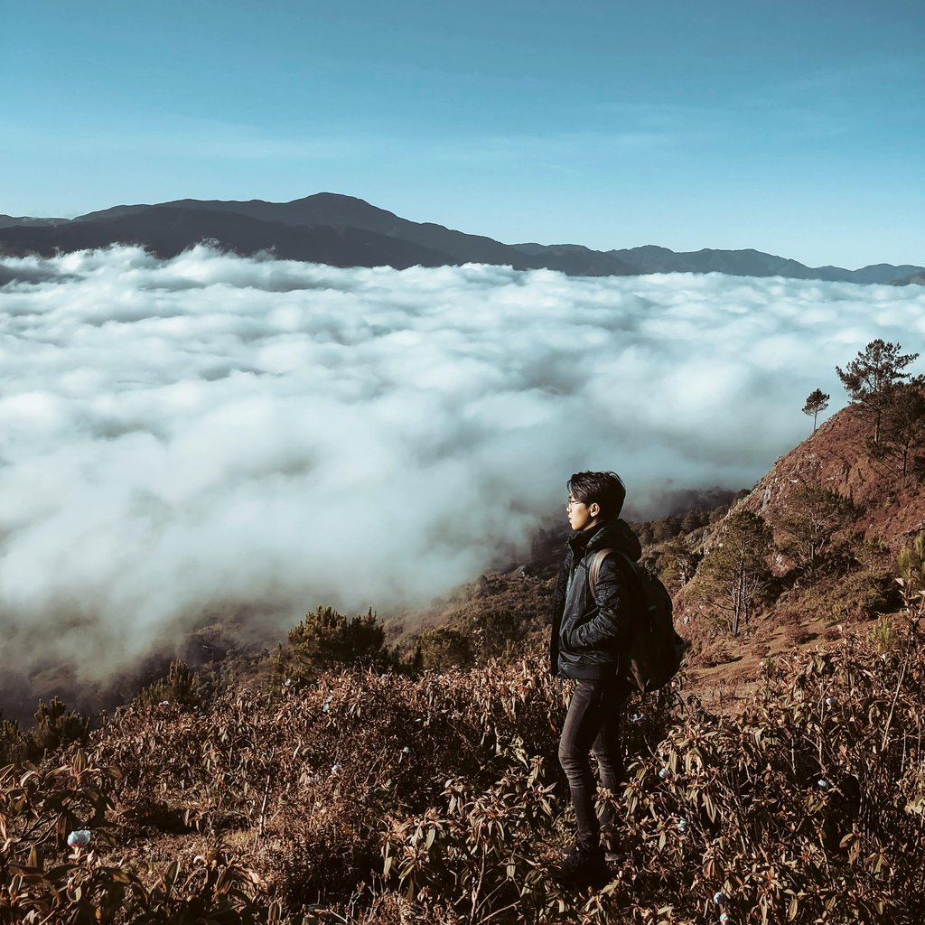 Man hiking with a backpack on a mountain in Sagada, Philippines, under a clear sky.
