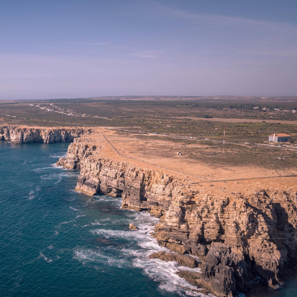 A stunning aerial view of the rocky coastline in Sagres, Portugal, showcasing cliffs and the Atlantic Ocean.