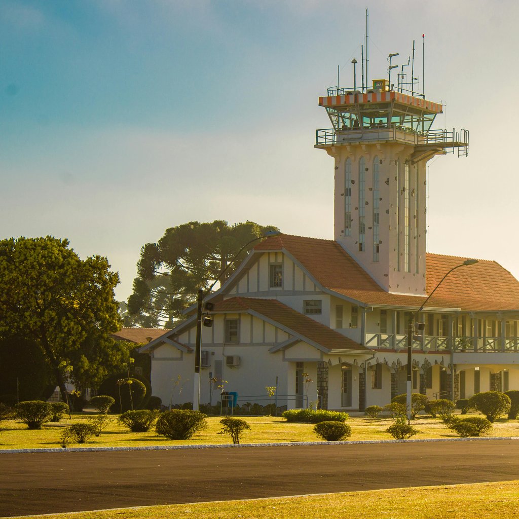 A scenic view of an airport control tower surrounded by sunlight and greenery.