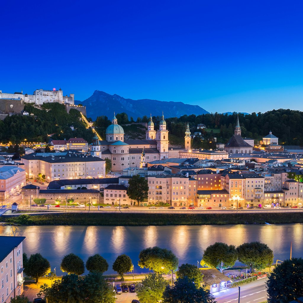 A breathtaking view of Salzburg cityscape with the illuminated Hohensalzburg Fortress at dusk.
