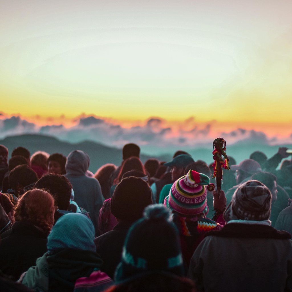 A colorful crowd gathers at sunset in Samaipata, Bolivia, against a stunning mountain backdrop.