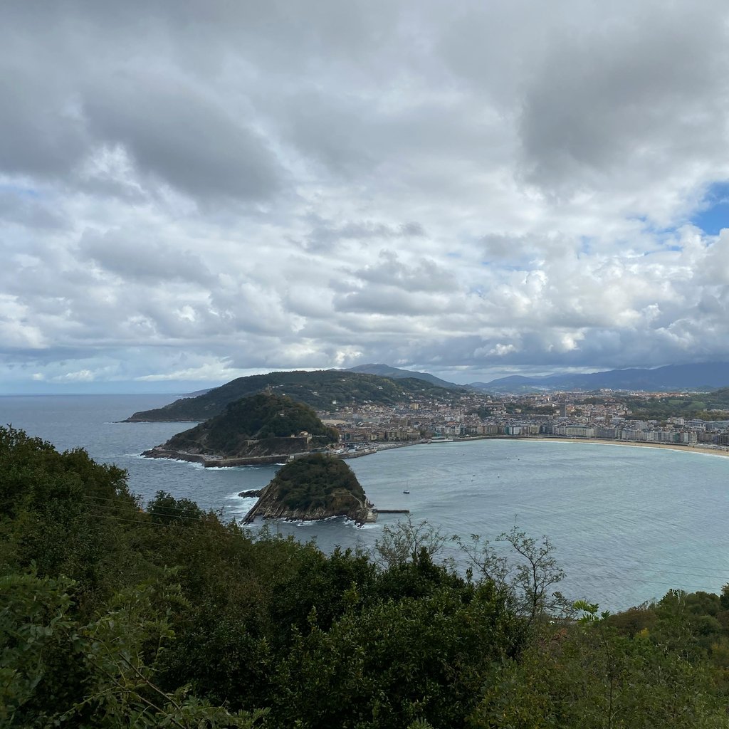 Breathtaking aerial view of the famous La Concha Bay, San Sebastian, showcasing the coastline and cityscape under a cloudy sky.