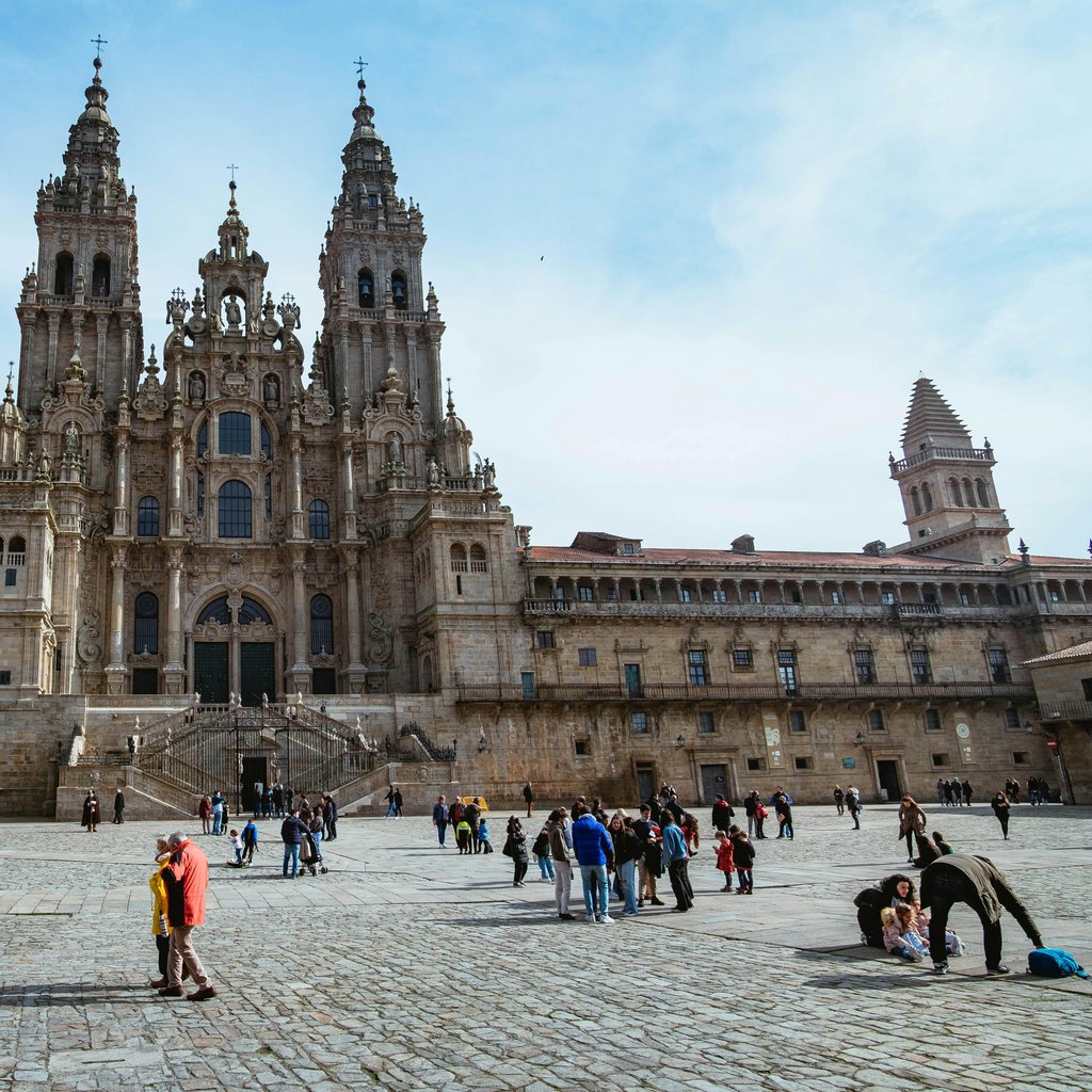 Stunning view of Santiago de Compostela Cathedral with people enjoying the sunlit plaza.