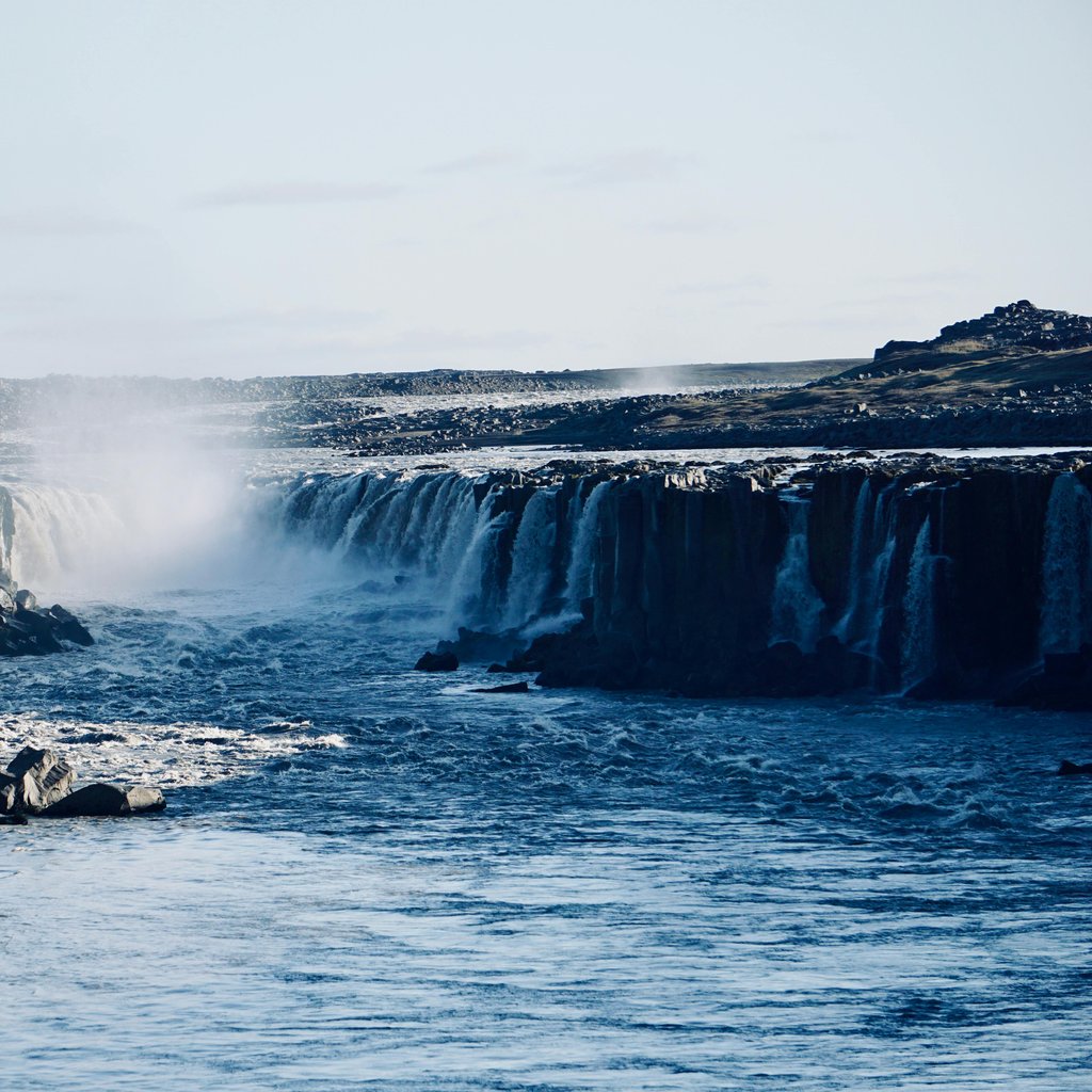 Breathtaking view of Selfoss waterfall cascading over Iceland's dramatic rocky cliffs under a clear sky.