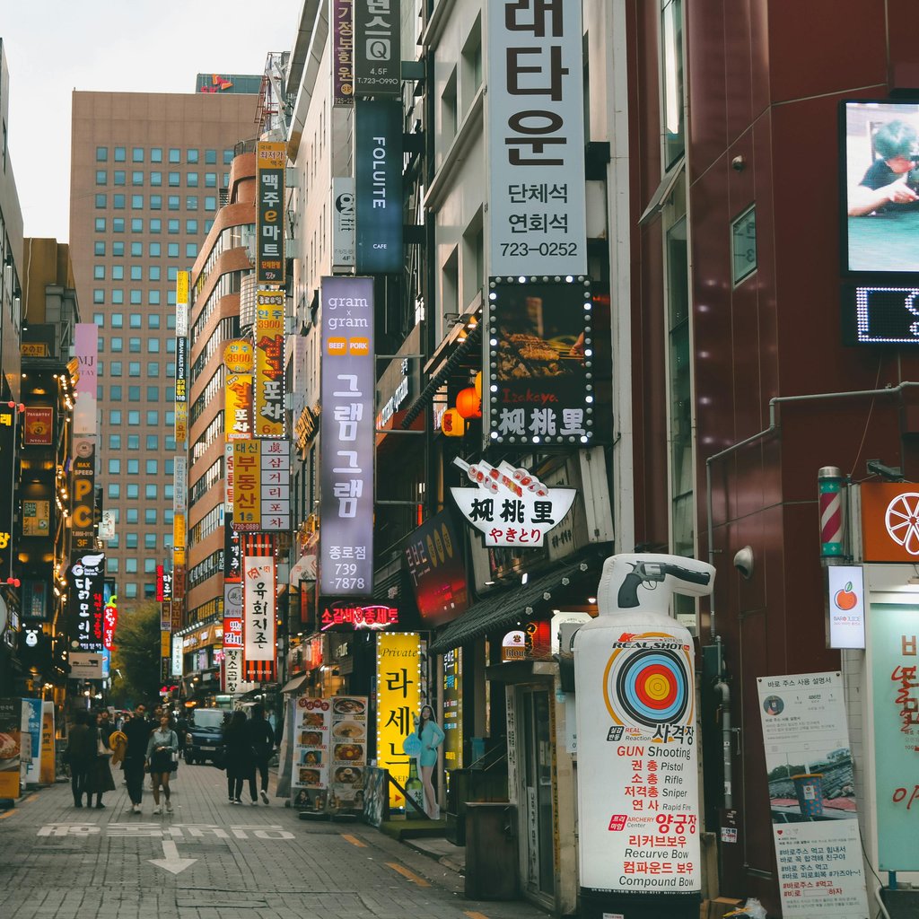 Bustling street in Seoul with vibrant signs and people walking. Captures urban life in South Korea.