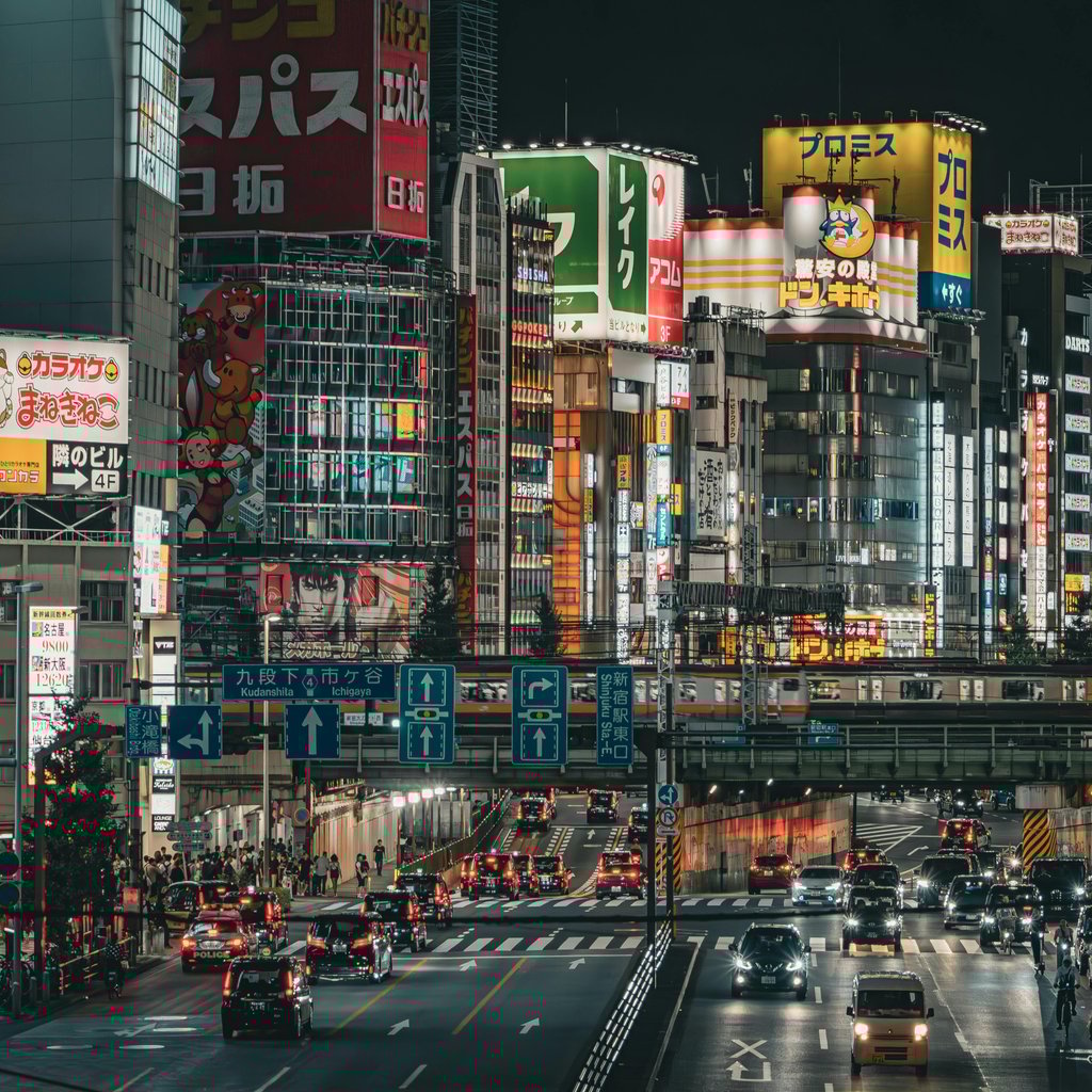 Bustling Shinjuku cityscape at night, Tokyo, showcasing neon lights and busy streets.