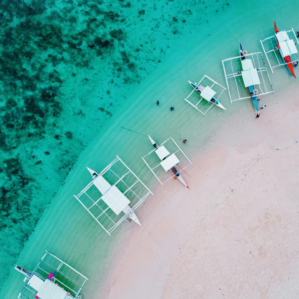 Aerial shot of traditional boats moored on the turquoise waters of Siargao Island's coast.