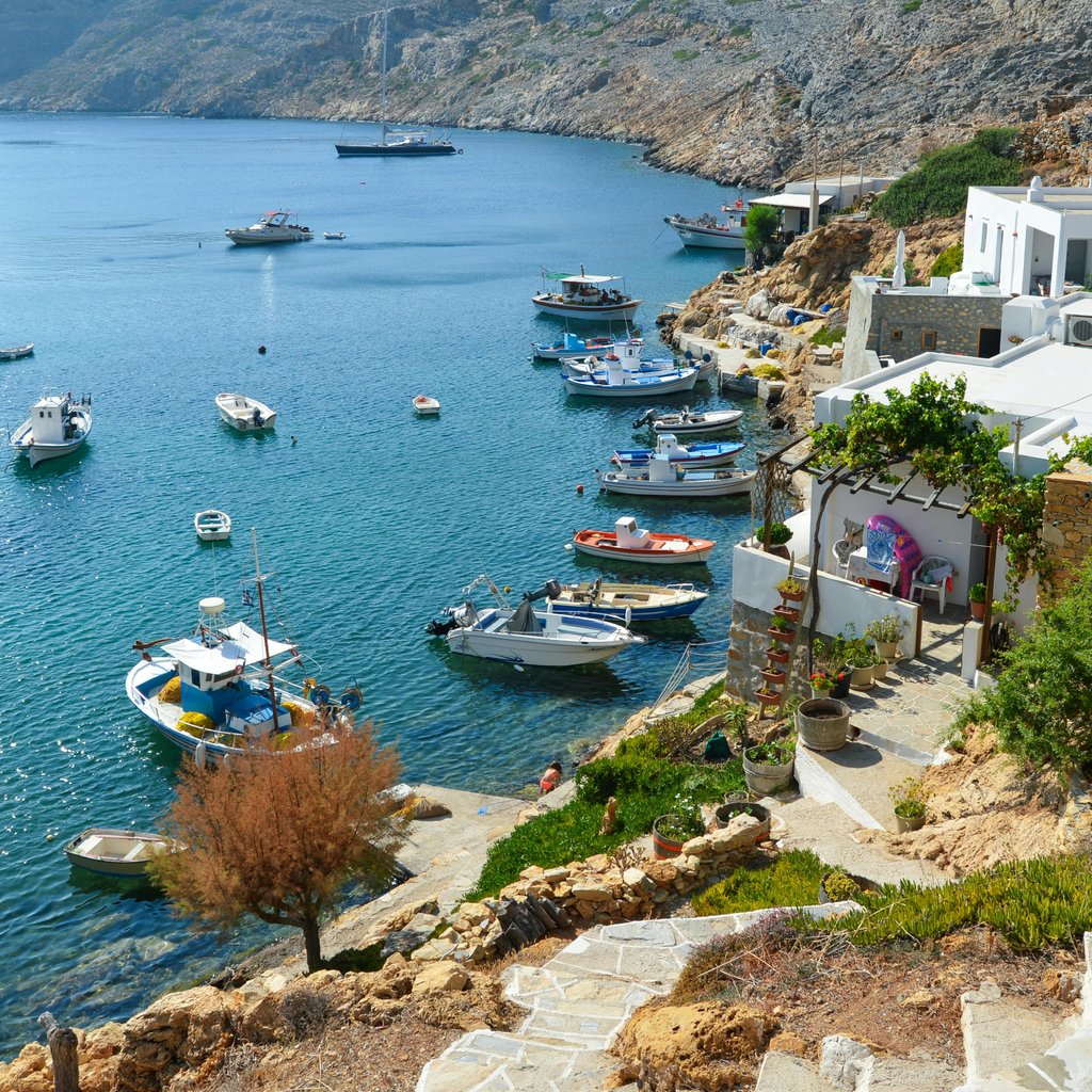 Picturesque view of a harbor with boats and traditional Greek architecture in Sifnos, Greece.