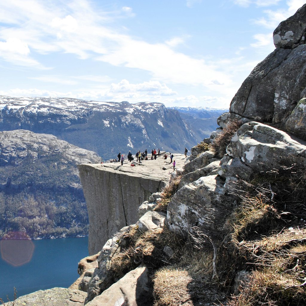 Tourists enjoy the breathtaking view from the famous Preikestolen cliff in Norway.