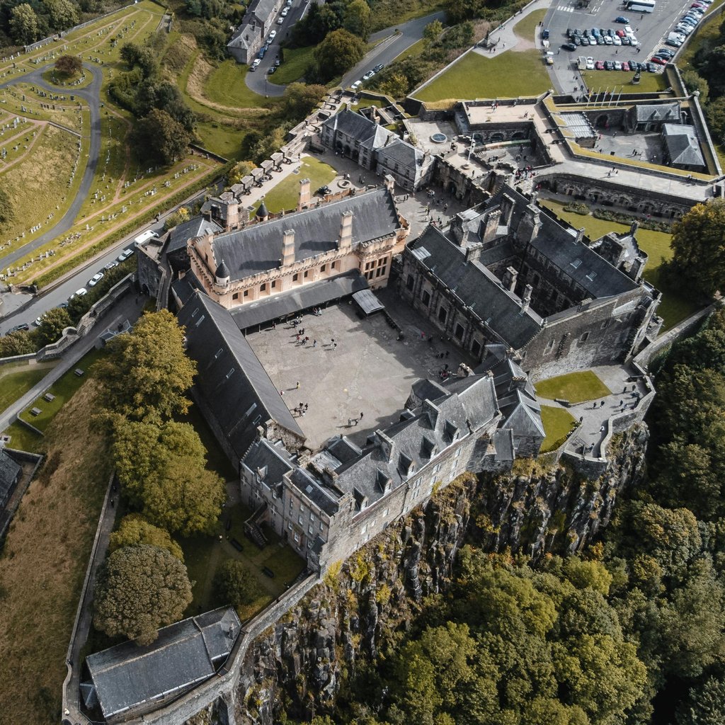 Discover the historic Stirling Castle from above, showcasing its stunning architecture and lush surroundings.