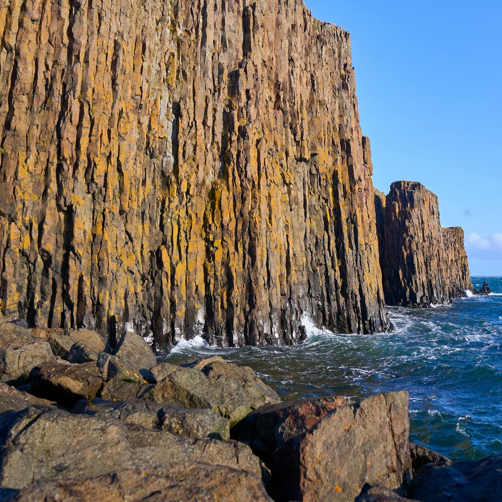Stunning view of towering basalt cliffs along the blue sea in Iceland, perfect for travel and nature enthusiasts.